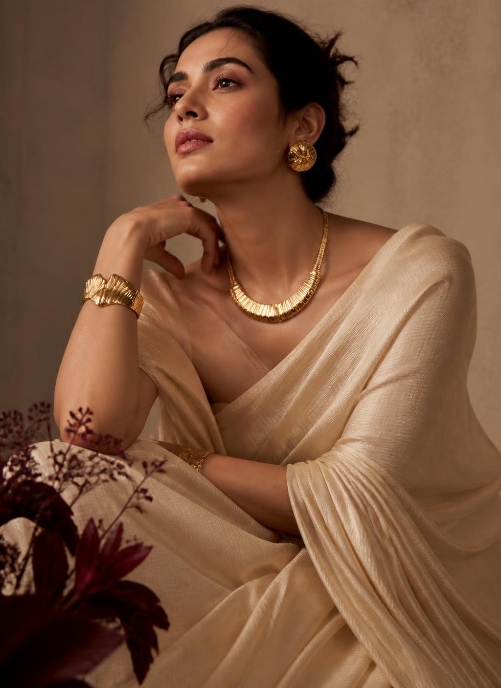 Editorial portrait of a woman wearing gold jewellery and ivory draped fabric